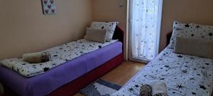 een slaapkamer met twee bedden en een raam bij Katarina apartman in Ribarska Banja