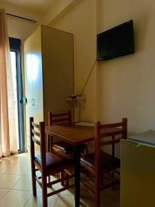 a dining room table and chairs with a television on the wall at Vila Mare in Shëngjin