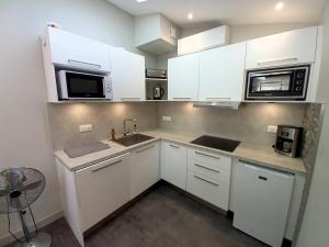 a kitchen with white cabinets and a sink and microwave at Saint Georges de Didonne - TOUT CONFORT et TOUT A PIED - APPARTEMENT au TOP in Saint-Georges-de-Didonne