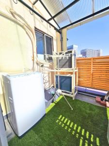 a balcony with green grass and a white refrigerator at 西九条がてんぼう in Osaka
