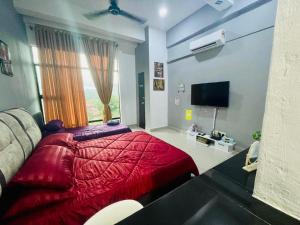 a bedroom with a red bed and a television at RZHOMESTAy in Gua Musang