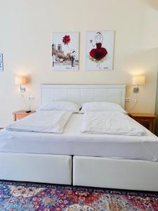 een wit bed in een slaapkamer met twee foto's aan de muur bij Apartment SMARAGD - direkt im Zentrum, Balkon in Bad Ischl +8 foto's