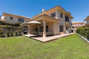 a large house with an umbrella in a yard at Casa Estelle - cozy with lovely garden - Mijas - Riviera del Sol in Mijas Costa