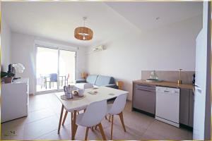 a kitchen with a white table and chairs in a kitchen at Résidence Roc e Mare in LʼÎle-Rousse