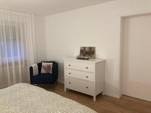 a bedroom with a white dresser and a chair at Geräumige Wohnung bei Basel in Grenzach-Wyhlen