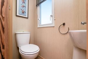 a bathroom with a toilet and a sink and a window at 3 Bed Caravan - Seton Sands in Port Seton +20 photos