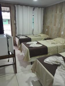 a group of three beds in a room at Hotel Europa de Itaguaí LTDA in Itaguaí