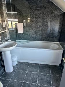 a bathroom with a white tub and a sink at The Valley Hotel, Anglesey in Valley +118 photos