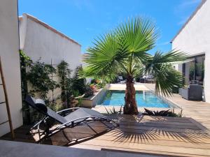 エーグ・モルトにあるLa Chambre Côté Piscineのヤシの木とスイミングプールのあるパティオ