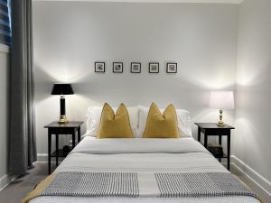 a bedroom with a bed with yellow pillows and two tables at Le Mimosa 32 nights min ExitChalets Lake in Morin Heights