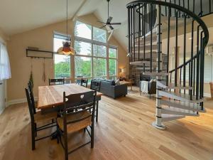 a dining room with a table and a spiral staircase at Le Mimosa 32 nights min ExitChalets Lake in Morin Heights