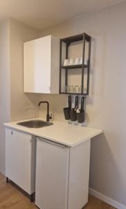 a kitchen with white cabinets and a sink at Cozy Retreat in the Heart of Ålesund in Ålesund