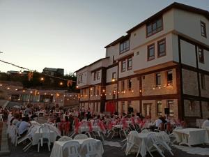 a group of people sitting at tables in front of a building at Kaşkaloğlu Hotel in Arapkir