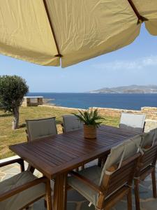a wooden table with chairs and an umbrella at Anemoessa in Naxos Chora