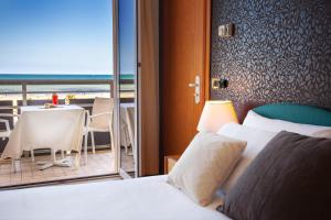 una camera d'albergo con letto e balcone con tavolo di Hotel Kursaal a Rimini