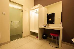 a bathroom with a sink and a shower with a red stool at Seven Hotel in Putatan