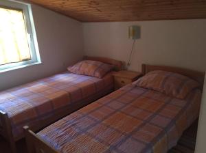 two beds in a small bedroom with a window at Apartman Antonia in Podhum