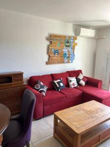 a living room with a red couch and a table at L'Arche de Porquerolles in Porquerolles