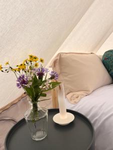 un vaso di fiori su un tavolo accanto a un letto di Mullichain Glamping a Saint Mullins