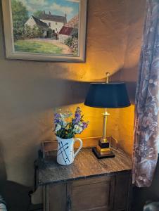 a table with a lamp and a vase of flowers on it at Riverside Cottage in Castledawson