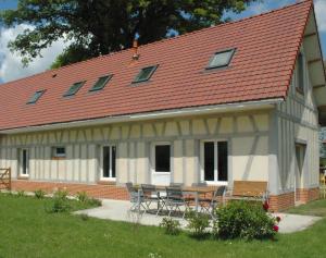 une maison avec une table et des chaises devant elle dans l'établissement Gîte Les Sources de l'Andelle, à La Ferté-Saint-Samson