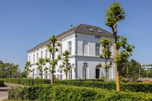 a large white house with trees in front of it at Boutique Hotel De Witte Dame in Abcoude