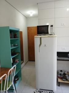 a kitchen with a microwave on top of a refrigerator at Kitnet mobiliada aconchegante in Londrina