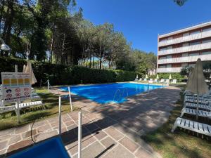 een zwembad met ligstoelen en een gebouw bij Euro Residence in Lignano Sabbiadoro