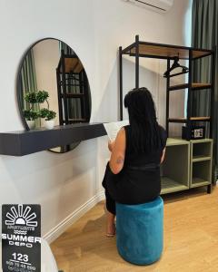 a woman sitting on a stool in front of a mirror at Summer Depo in Sarandë