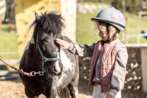 a woman is petting a black horse at Alpin Family Resort Seetal in Kaltenbach