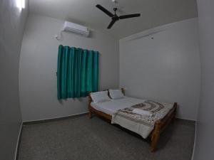 une chambre avec un lit et un ventilateur de plafond dans l'établissement Alpha Homestay, à Kāsarkod