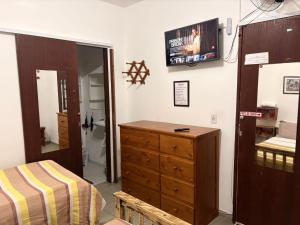 a bedroom with a dresser and a tv on the wall at Pousada Cantinho de Minas Da Tânia in Cabo Frio