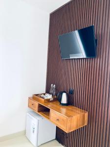 a wooden table with a tv on a wall at D'Tulak House in Ubud