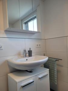 a bathroom with a white sink and a mirror at Ferienwohnung Wiese in Langelsheim +15 photos
