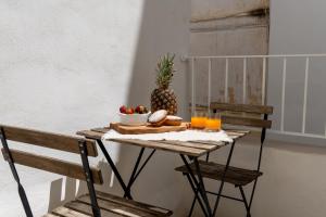 a table with a pineapple and a bowl of fruit and orange juice at Casa Dogana Apartment in Gallipoli