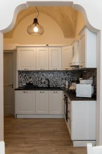 a kitchen with white cabinets and a ceiling at Casa Dogana Apartment in Gallipoli