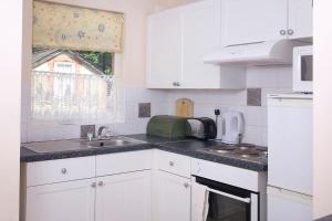a kitchen with white cabinets and a sink and a window at Woodcliffe Holiday Apartments in Ventnor
