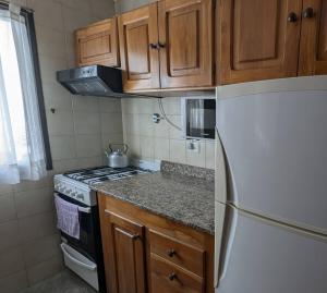 a kitchen with a white refrigerator and wooden cabinets at Departamento Costa del Lago Bariloche in San Carlos de Bariloche