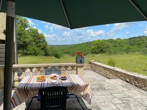 a table and chairs on a patio with an umbrella at Domaine Rossignol Tournesol in Gourdon-en-quercy
