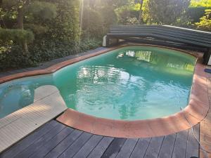 a swimming pool with a bench and a wooden deck at Chez Clark et Elo in Bréançon