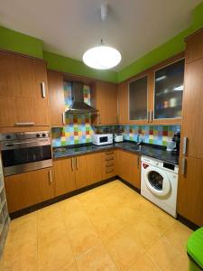 Una cocina con muebles de madera y lavadora. en VUT A Casa da Herba, en Redondela