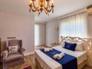 a bedroom with a bed and a chair and a chandelier at Villa Limon in Kuşadası