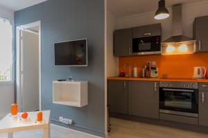 une cuisine avec des placards gris et un mur orange dans l'établissement Sweet Home Dijon-Arquebuse, à Dijon