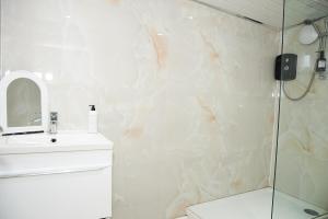 a white bathroom with a shower and a sink at West Yorkshire Stay - Heart of Leeds in Roundhay