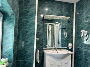 a blue tiled bathroom with a sink and a mirror at Avenue Palm Eforie in Eforie Nord