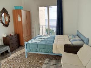 a bedroom with a bed and a couch and a window at Akri Rooms in Akrata