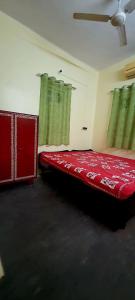 a bedroom with a red bed with green curtains at Mandira's Home in Kolkata +20 photos
