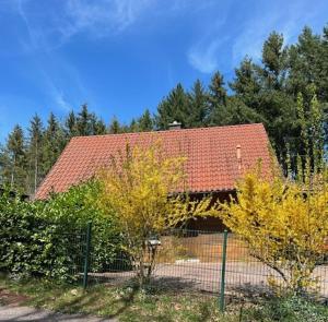 ein Haus mit rotem Dach und einem Zaun in der Unterkunft Ferienhaus Leonie, Holzhaus im Pfälzer Wald 76848 Hofstätten 