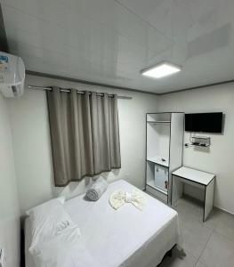 a bedroom with a white bed and a television at Hotel King Palace - Hotel Irituia in Irituia