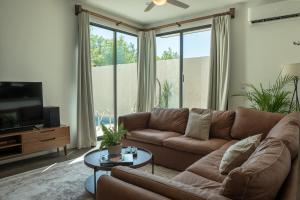 a living room with a brown couch and a tv at Casa Eva -Ocean View Rooftop, Pool - La Punta in Puerto Escondido
